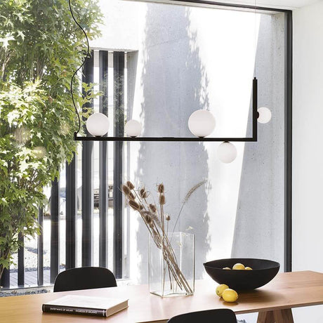 Elegant Birds pendant light, 5-light, above a wooden table in a modern room with plants.