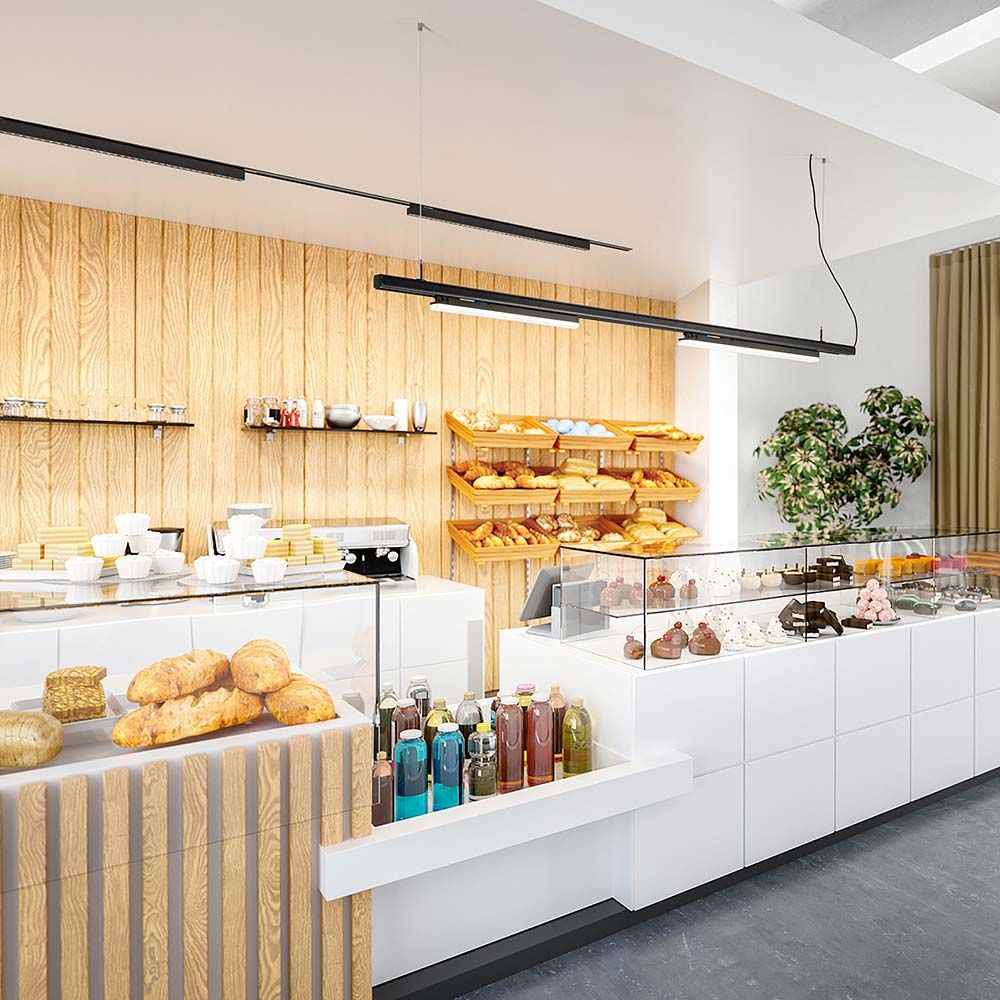 Moderne Bäckerei-Umgebung mit LED-Beleuchtung, Holzregalen und einem Sortiment an Gebäck und Getränken.