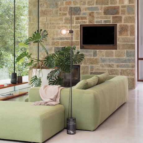 Eva floor lamp with marble base next to a modern sofa in a stylish living space.