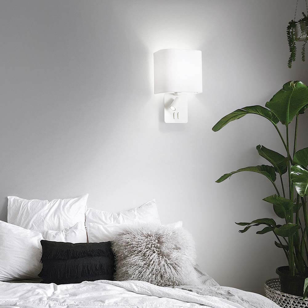 Gea Map Wandlampe mit LED Leselicht an einer Wand über einem Bett mit Pflanzen dekoriert.