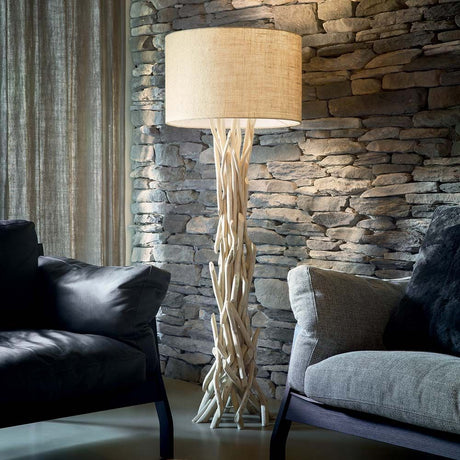 Gulvlampe Driftwood Pt1 i moderne boligmiljø med steinmur og elegante sofaer.