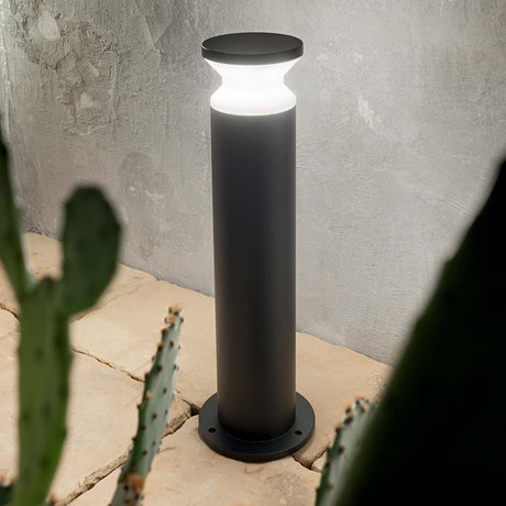 Floor lamp Torre Pt1 Large Black in a modern design with soft light on a path in a garden.