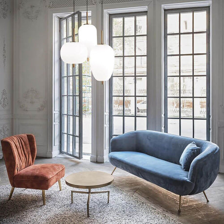 Umile SP3 Pendelleuchte über einem blauen Sofa und einem roten Sessel in einem modernen Wohnraum.