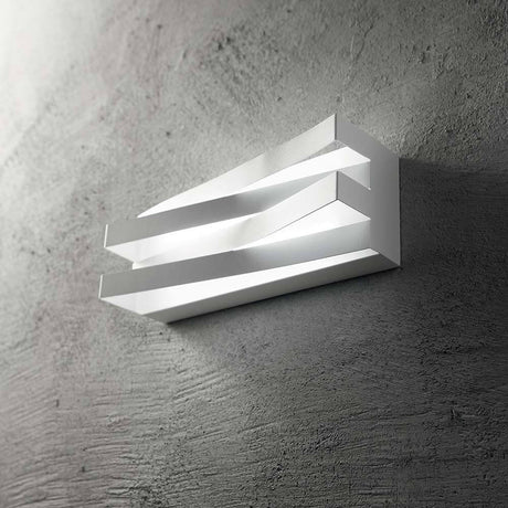 Applique murale Virtus LED en métal et acrylique montée sur un mur en béton, design moderne et lumière chaleureuse.