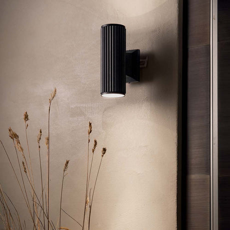 Wall light Base Ap2 Black on a wall with decorative grasses in the foreground.