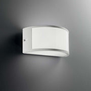 Wandleuchte Rex-1 Ap1 Weiß an einer grauen Wand montiert mit modernem Design.