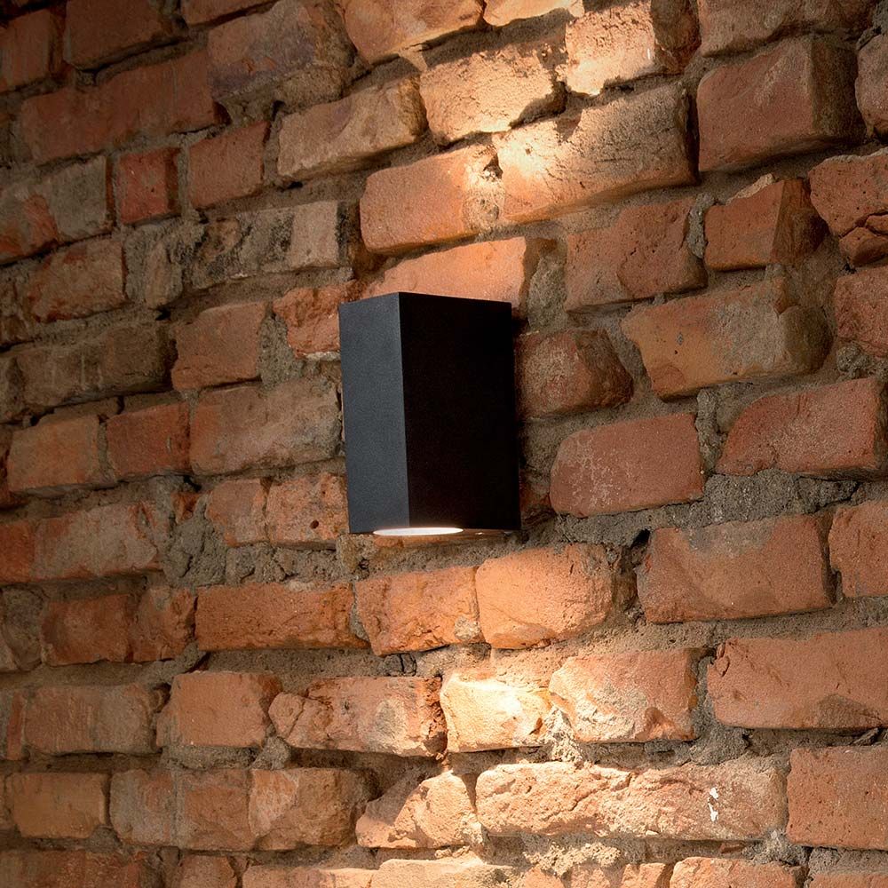 Wandleuchte Up Ap2 Schwarz an einer Backsteinwand montiert, elegante Wandbeleuchtung im minimalistischen Design.