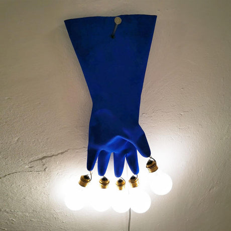 Ingo Maurer LED Applique murale Luzy On The Wall gant en caoutchouc bleu sur un mur avec des ampoules lumineuses.