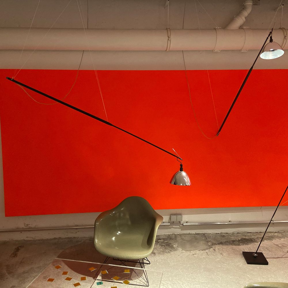 Ingo Maurer Max. Mover LED Lampe mit flexiblem Teleskopstab in modernem Raum, orangefarbener Wand.