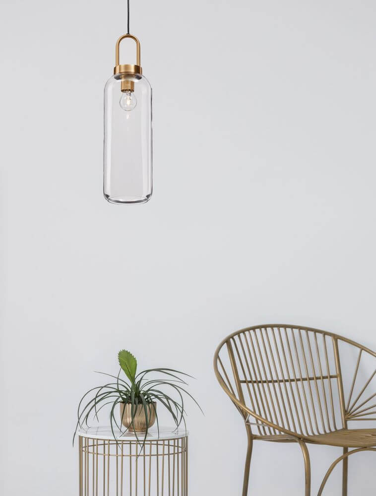 Irvine Pendelleuchte Ø 15,5cm Gold, Transparent über einem Tisch mit Pflanze in modernem Wohnambiente.