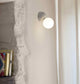 Joy LED Wandlampe Opalglas an einer Wand, modernes Design mit runder Opalglas-Diffusor.