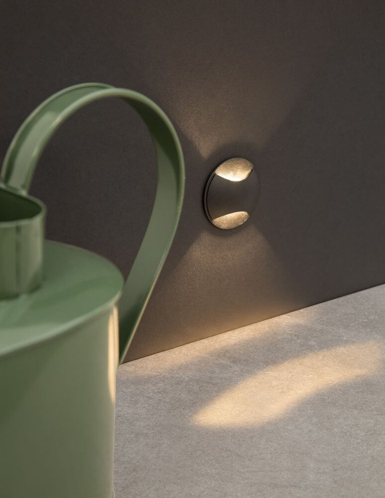 Joya LED Außenwandeinbauleuchte Up & Down 3000K Schwarz IP65 an Wand mit grünem Gießkanne.