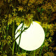 Lampe d'extérieur LED sans fil Pearl avec contrôle par application dans des plantes éclatantes, crée une ambiance lumineuse à l'extérieur.