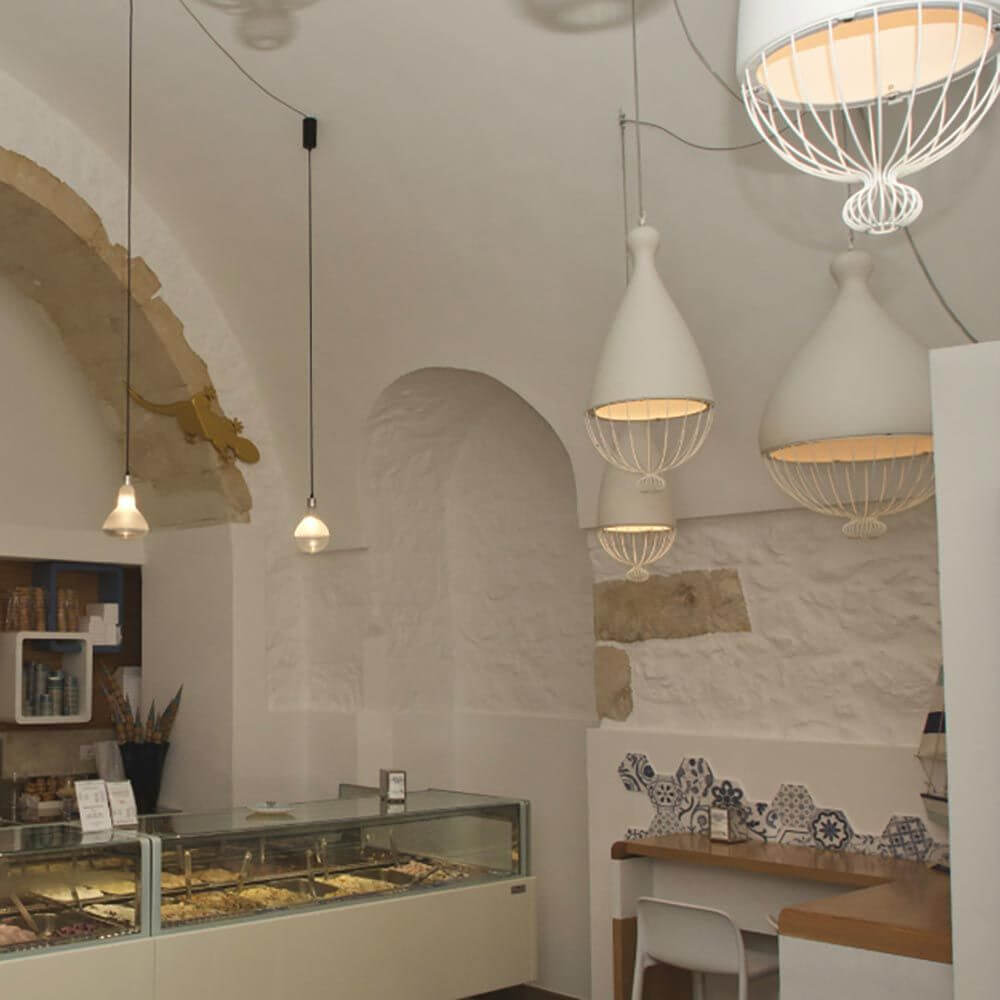 Karman Hängeleuchte Le Trulle in einem modernen Eiscafé mit hellem Innendesign und künstlerischer Ausleuchtung.