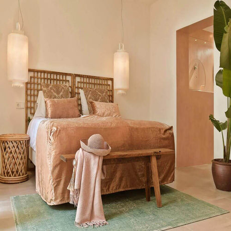 Karman Kimono Hängeleuchte über einem stilvollen Bett in hellen, eleganten Schlafzimmer mit Naturdekor.