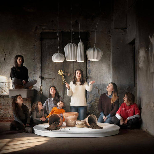 Karman Sahara pendant light above a group of people in a dimly lit room, creating a creative atmosphere.