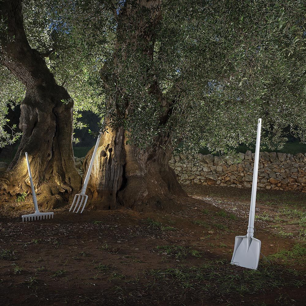 Weiße Schaufel und Rechen stehen neben Olivenbäumen, kombiniert mit Karman Tobia LED-Stehlampe im Freien.