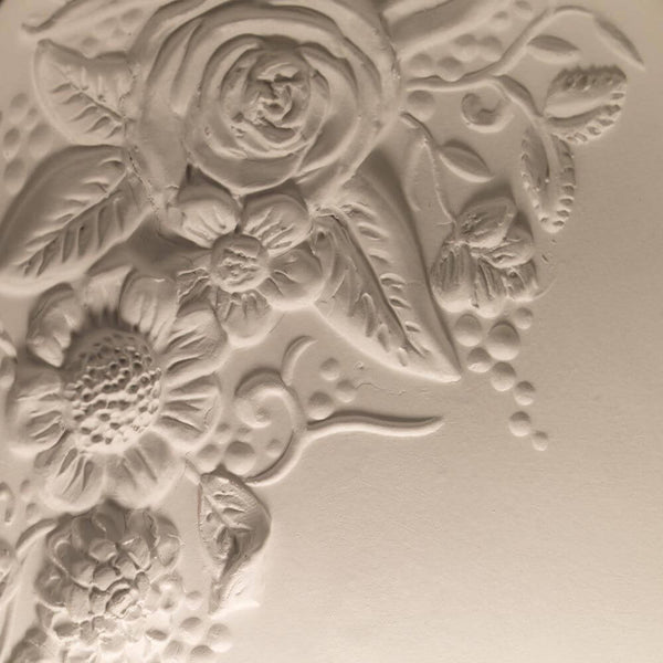 Gros plan d’un motif floral en relief sur un fond clair.