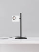 Kedros LED Tischleuchte 3000K mit Lampenfuß auf einem weißen Tisch, modernes Design aus Stahl und Aluminium.