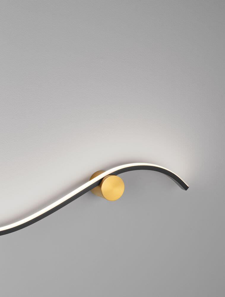 Kima LED Wandleuchte Geschwungen 3000K Schwarz, Gold an einer Wand in stilvollem Design.