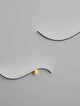 Kima LED Wandleuchte Geschwungen 3000K Schwarz, Gold an grauer Wand, stilvolles Design mit goldenen Akzenten.