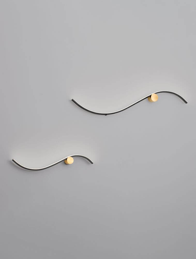 Kima LED Wandleuchte Geschwungen 3000K Schwarz, Gold an einer Wand montiert, modernes Design.