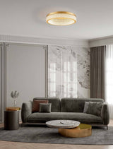 Kinara Deckenleuchte 3000K Gold in modernem Wohnraum mit grauem Sofa und eleganten Wohnaccessoires.