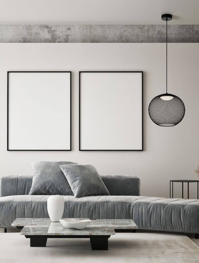 Moderne KINETIC Pendelleuchte aus schwarzem Drahtgeflecht in stilvollem Wohnzimmer mit leeren Bilderrahmen.