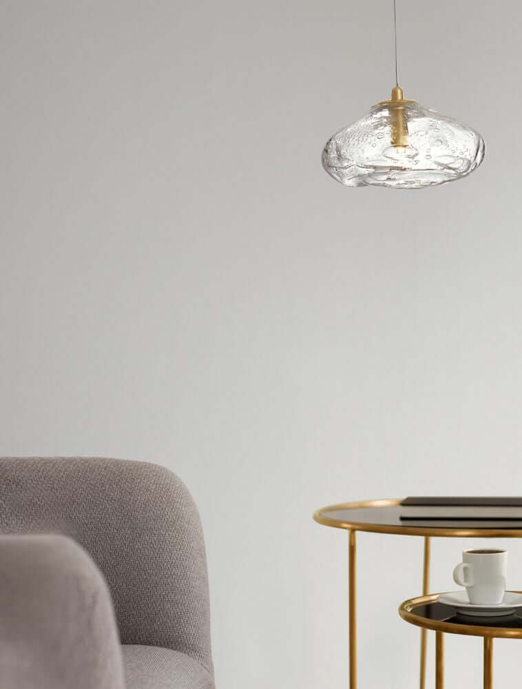 King Pendelleuchte G9 Gold, Transparent über einem Tisch mit einem Becher und Buch.