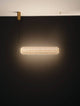 Klelia Pendelleuchte Horizontal 3000K Gold an einer Wand, elegantes Design mit goldener Halterung und warmem Licht.