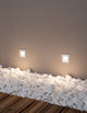 Krypton LED Außenwandeinbauleuchte quadratisch mit 3000K Weißlicht, IP54, an Wand mit Kies.
