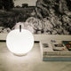 Kundalini LED Akku-Tischlampe Kushi in runder Form, dekorativ auf Tisch mit Zeitschriften platziert.