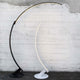 Kundalini LED Bogen-Stehlampe Kyudo Dimmbar in den Farben Schwarz und Weiß vor grauer Wand.