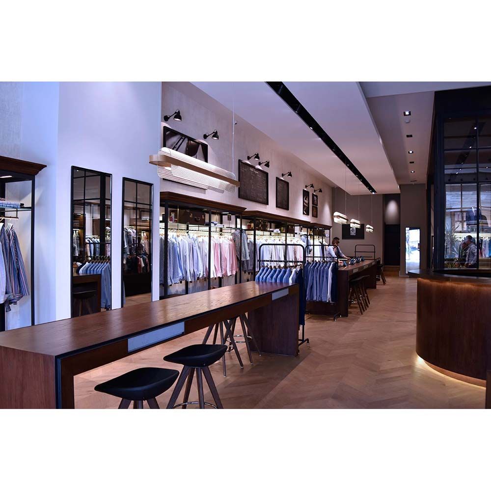 Moderne Boutique mit Holzregalen und stilvollen Tischen, präsentiert eine Auswahl an Hemden.