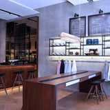 Moderne Boutique mit Holztheke, eleganten Barhockern und stilvoller Beleuchtung im Hintergrund.