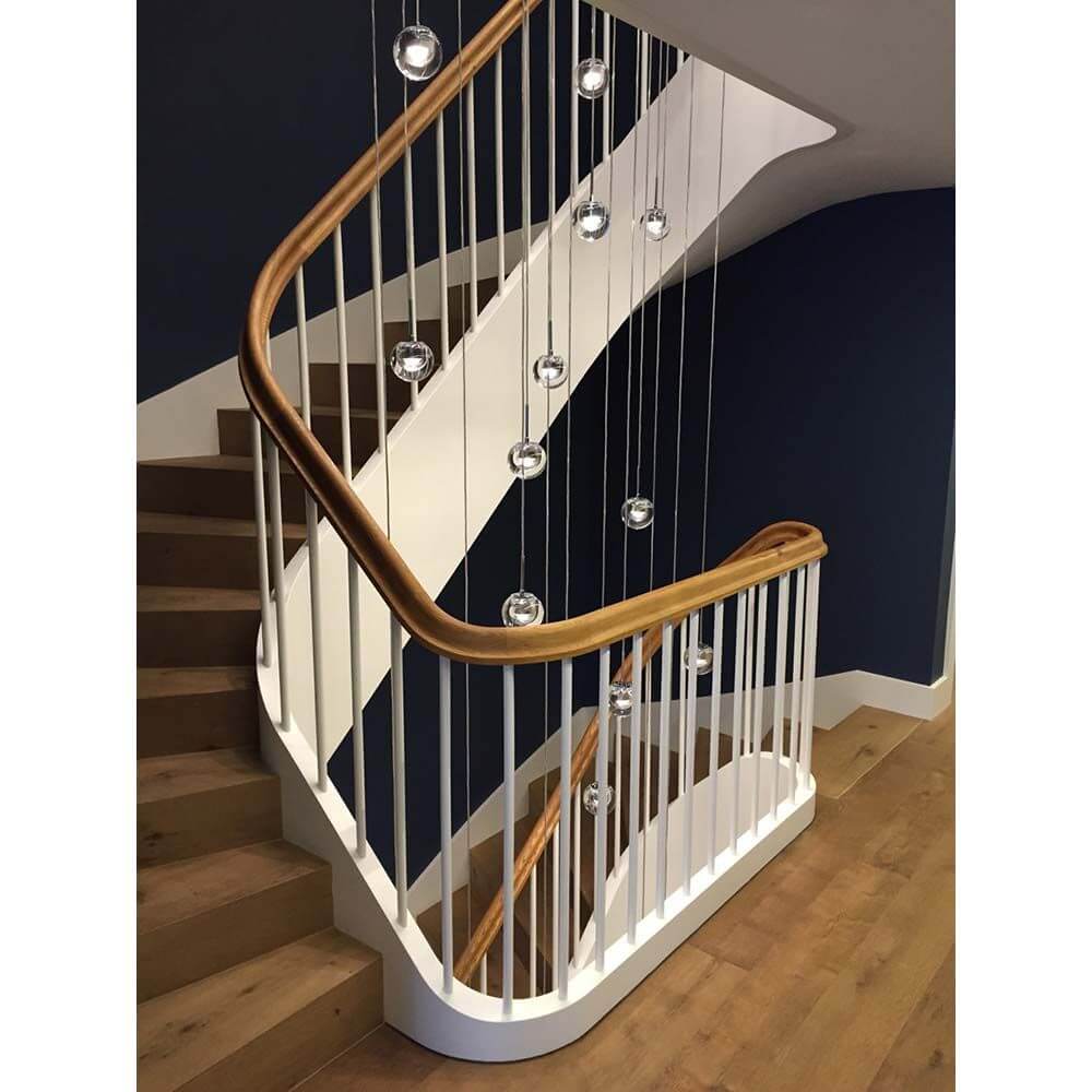 Moderne Treppe mit elegantem Handlauf und stilvollen hängenden Leuchten, die eine einladende Atmosphäre schaffen.