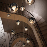 Kundalini LED Pendellampe DEW in einer eleganten Treppenhaus-Installation mit dimmbaren Lichtern.
