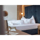 Schlafzimmer mit modernem Bett, weißen Kissen und Bettdecken, stilvolle Raumbeleuchtung und Holzdekor.