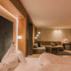 Modernes Schlafzimmer mit Kushi Pendellampe, Holzdetails und gemütlicher Sitzecke, warmes Licht.