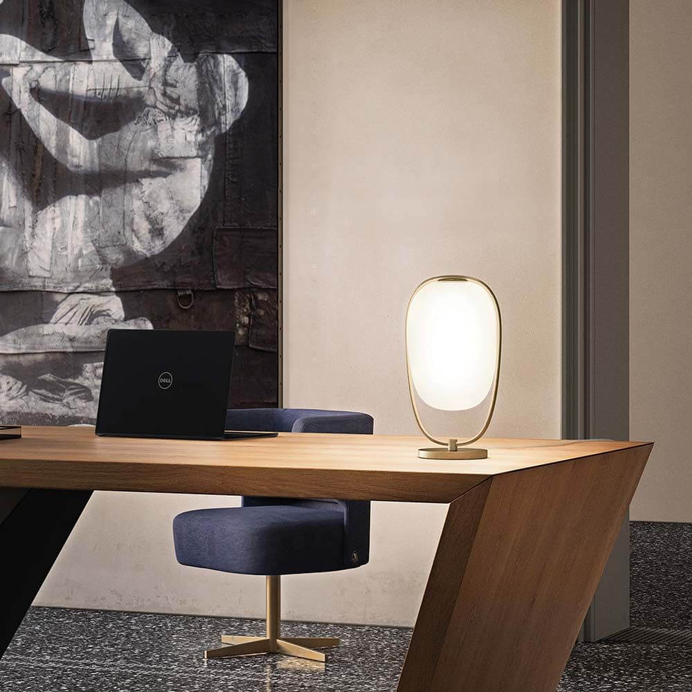 Kundalini Tischleuchte Lanna 40cm mit Glasschirm auf einem modernen Schreibtisch mit Kunst im Hintergrund.