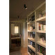 LED Wandstrahler STAN 12W 2700K Schwarz an Decke über Bücherregal in modernem Raum.
