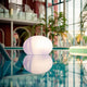 LED Akkulampe Flatball L mit App-Steuerung schwimmend auf Wasseroberfläche in modernem Ambiente.
