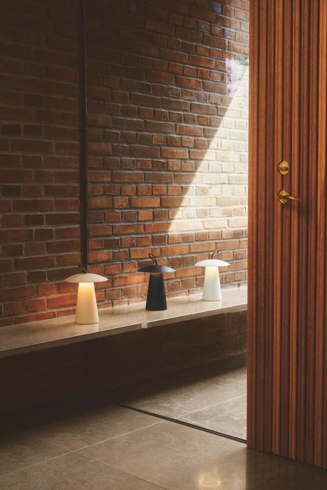 LED Akkuleuchte Ara To-Go 2 IP54 in modernem Raum mit Backsteinwand und eleganter Tür.