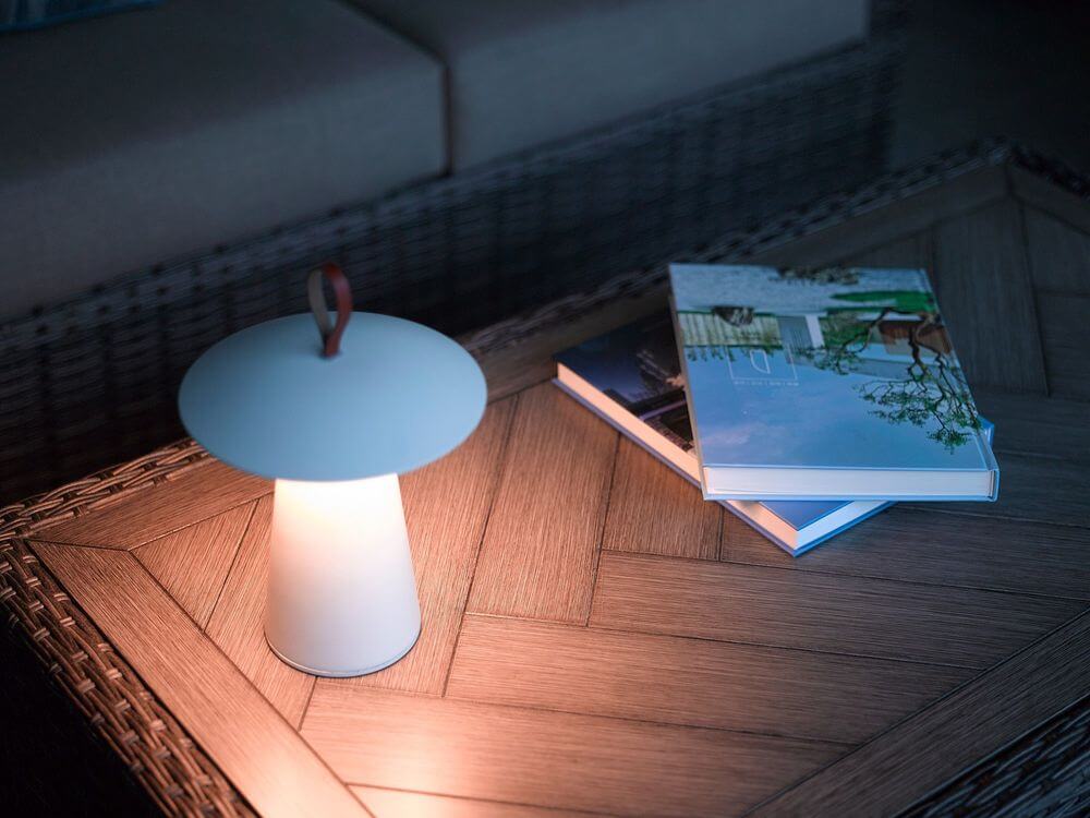 LED Akkuleuchte Ara To-Go IP54 auf einem Tisch mit Büchern in einem stilvollen Ambiente.