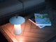 LED Akkuleuchte Ara To-Go IP54 auf einem Tisch mit Büchern in einem stilvollen Ambiente.