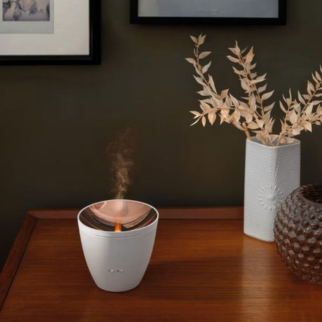 LED Aroma Diffuser Zoe candeeiro de mesa com luz de efeito sobre uma mesa de madeira com nevoeiro e decoração.