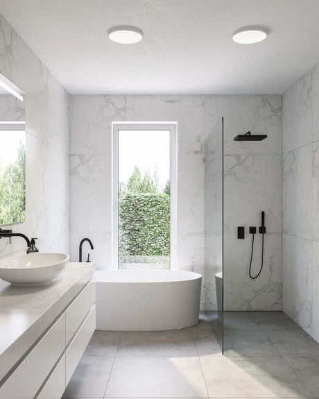 LED Spot de montage en saillie Sóller 22 -44 dans une salle de bain moderne avec une baignoire élégante et une paroi de douche en verre.