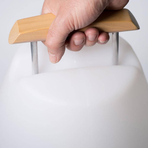 Hand holding the wooden handle of the LED outdoor decorative lamp Vessel 1 battery-operated with app control.
