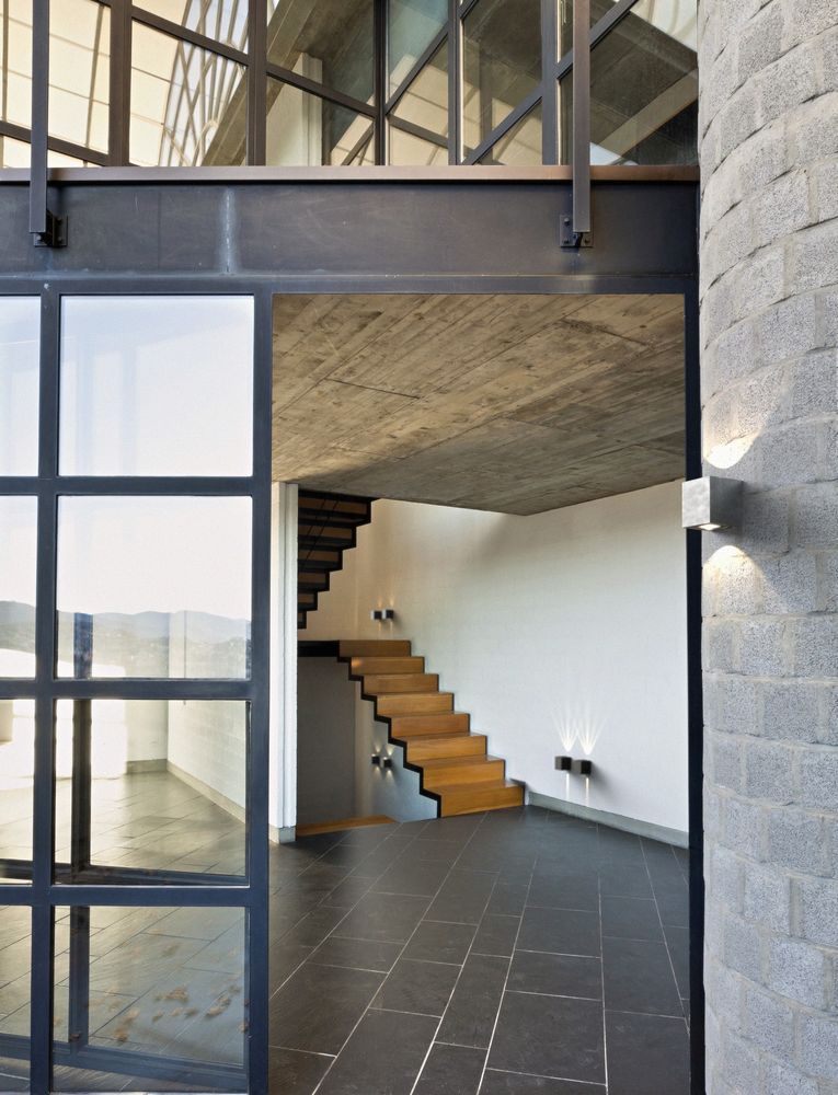 Heller Eingangsbereich mit modernen Stufen, großen Fenstern und minimalistischer Architektur.