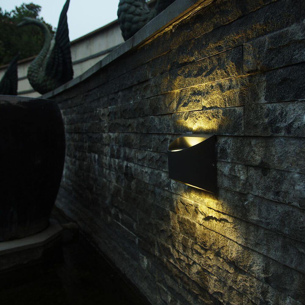 LED Außen-Wandleuchte Dodd IP54 Anthrazit an einer Steinwand mit warmem Licht.